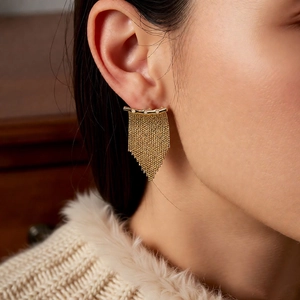 Gros plan de boucles d'oreilles à pampilles plaquées or 14K avec zircons portées par un modèle