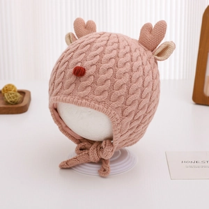 Detailed close-up of pink cable knit baby winter hat with cute 3D reindeer antlers