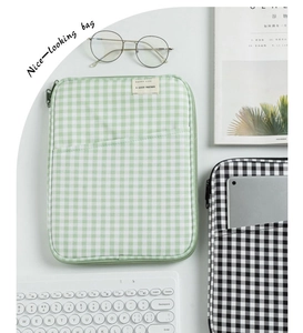 Detailed view of the dual-compartment checkered laptop sleeve with embroidered label