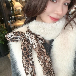 Close-up of luxury white faux fur scarf with a stylish leopard print silk ribbon bow