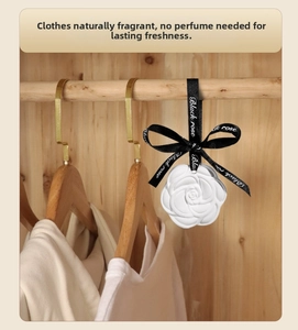 White rose scented plaster freshener with black ribbon hanging in a wooden wardrobe