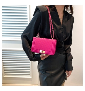 Detail of rose red chain crossbody bag with gold lock and quilted stitching on model