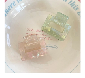 Close-up of square mermaid hair claws in iridescent light green and pink finish
