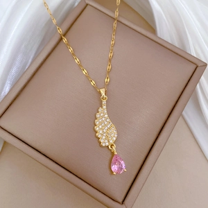 Gold angel wing necklace with pink teardrop crystal on luxury white silk background