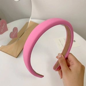 Pink fabric wide headband with brown lining displayed on a clean white desk with a mirror
