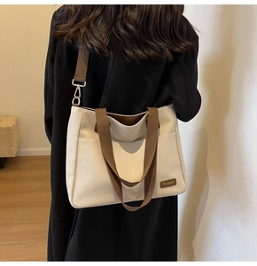 Detail of cream canvas tote bag with brown straps and Banatu logo tag on shoulder