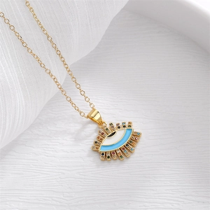 Golden necklace with blue Evil Eye pendant and colorful zircon stones on white background