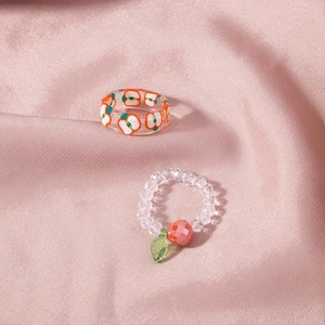 Detail of clear fruit rings set with red apple pattern and orange beaded charm