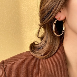 Close-up of model wearing large gold hoop earrings with sparkling rhinestones for women