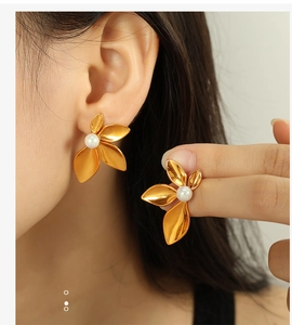 Close-up of elegant 18K gold-plated flower stud earrings with white pearls on a model