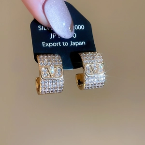Macro shot of gold-plated hoop earrings with micro-pave zircon stones and V logo detail