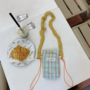 Detail of plaid mini crossbody phone bag with yellow pleated cloud strap and side drawstring