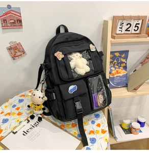 Dettaglio dello zaino scuola in nylon nero con tasche in PVC e ciondoli in peluche