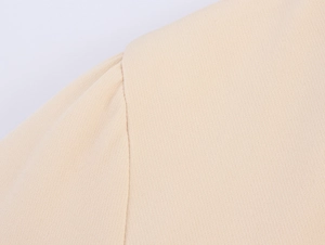 Close-up of beige woven fabric texture and shoulder seam on a professional suit blazer