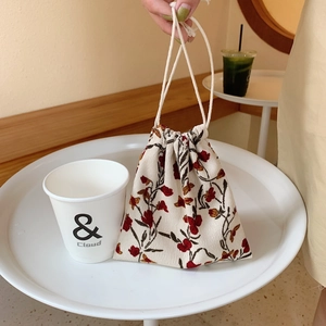 Close-up of a floral drawstring pouch on a cafe table with a white paper cup