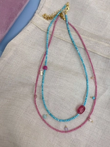 Detailed macro view of layered turquoise and pink natural stone beaded necklaces