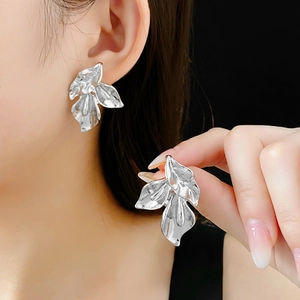 Détail macro de grandes boucles d'oreilles pétales argentées sur un modèle