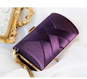Close-up of deep purple satin evening bag with pleated texture and gold tassel detail