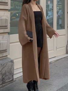Photo de rue montrant une femme portant un long cardigan en maille marron avec bottes en cuir