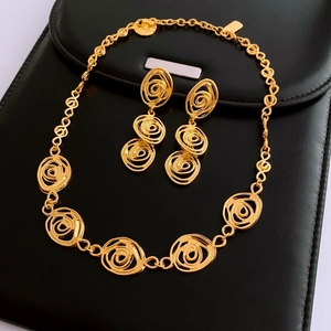 Detail of vintage gold spiral jewelry set featuring carved flower earrings and necklace
