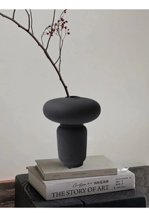 Dettaglio di un vaso in ceramica nera opaca dal design a strati con ramo decorativo di bacche rosse
