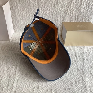 Detail of blue denim baseball cap interior featuring orange stitching and adjustable strap