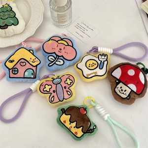 Flat lay of colorful plush cartoon charms with embroidery details on a white background