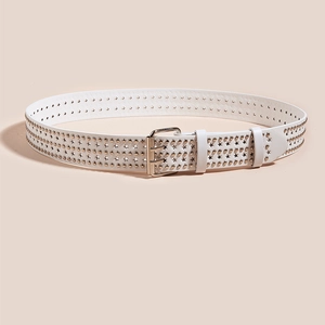 Détail d'une ceinture en cuir blanc avec clous étoiles dorés et boucle métallique