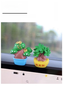 Close-up of cute resin lucky tree and blue pine car dashboard decor on central console