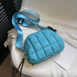 Close-up of quilted blue nylon crossbody bag with adjustable wide strap and knotted zipper