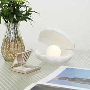 Minimalist white shell night light with glowing pearl on a nightstand for home decor