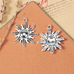 Vintage 25mm silver sun alloy charms on a rustic background for DIY jewelry making