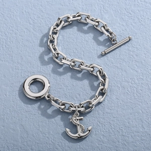 Detailed shot of silver anchor charm bracelet with toggle clasp on textured blue surface