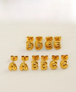 Detail of 18K gold-plated bubble letter stud earrings with polished metal finish
