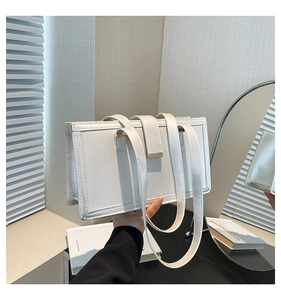 Detail of white oil leather tote with gold metal buckle shown in a vintage lifestyle setting