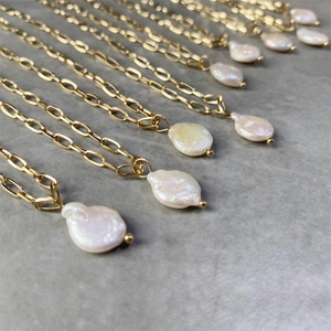 Múltiples collares chapados en oro con perlas barrocas irregulares sobre fondo gris