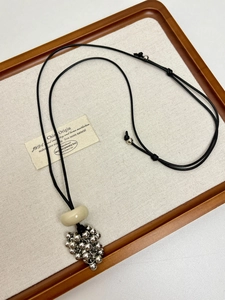 Détail du collier grappe de raisin avec boules argentées et cordon ciré noir