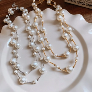 Detailed view of gold and silver pearl necklaces displayed on a decorative ceramic plate