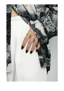 Detail of gold textured rings with blue and white zircons on model's hand
