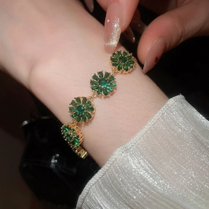 Detail of 18k gold plated bracelet featuring sparkling green zircon flower charms