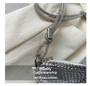 Detail view of silver rhinestone handbag with luxury crystal strap and metallic zipper