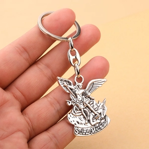 Close-up of Saint Michael slaying dragon silver metal keychain held in hand
