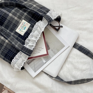 Detailed view of plaid tote bag with lace trim, holding magazine and tablet for capacity
