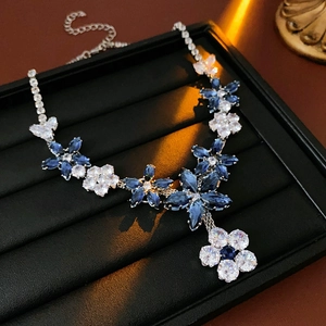 Close-up of elegant blue and white crystal flower necklace on a black jewelry stand