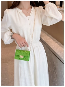Detail of green quilted jelly bag featuring a pearl handle and golden chain strap