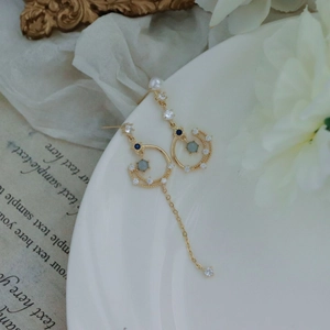 Close-up of asymmetric gold tassel earrings with crescent moon and zircon stones