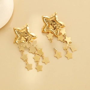 Macro shot of gold star tassel earrings with hammered texture and smooth surface detail