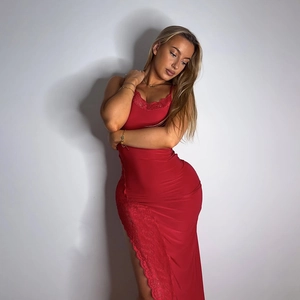 Dettaglio dell'abito in raso rosso con pizzo e spacco alto su una modella