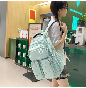 Detail of light blue school backpack featuring cute cartoon bear prints and multi-pocket design