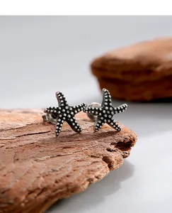 Macro shot of vintage silver starfish earrings with textured surface on rustic wood